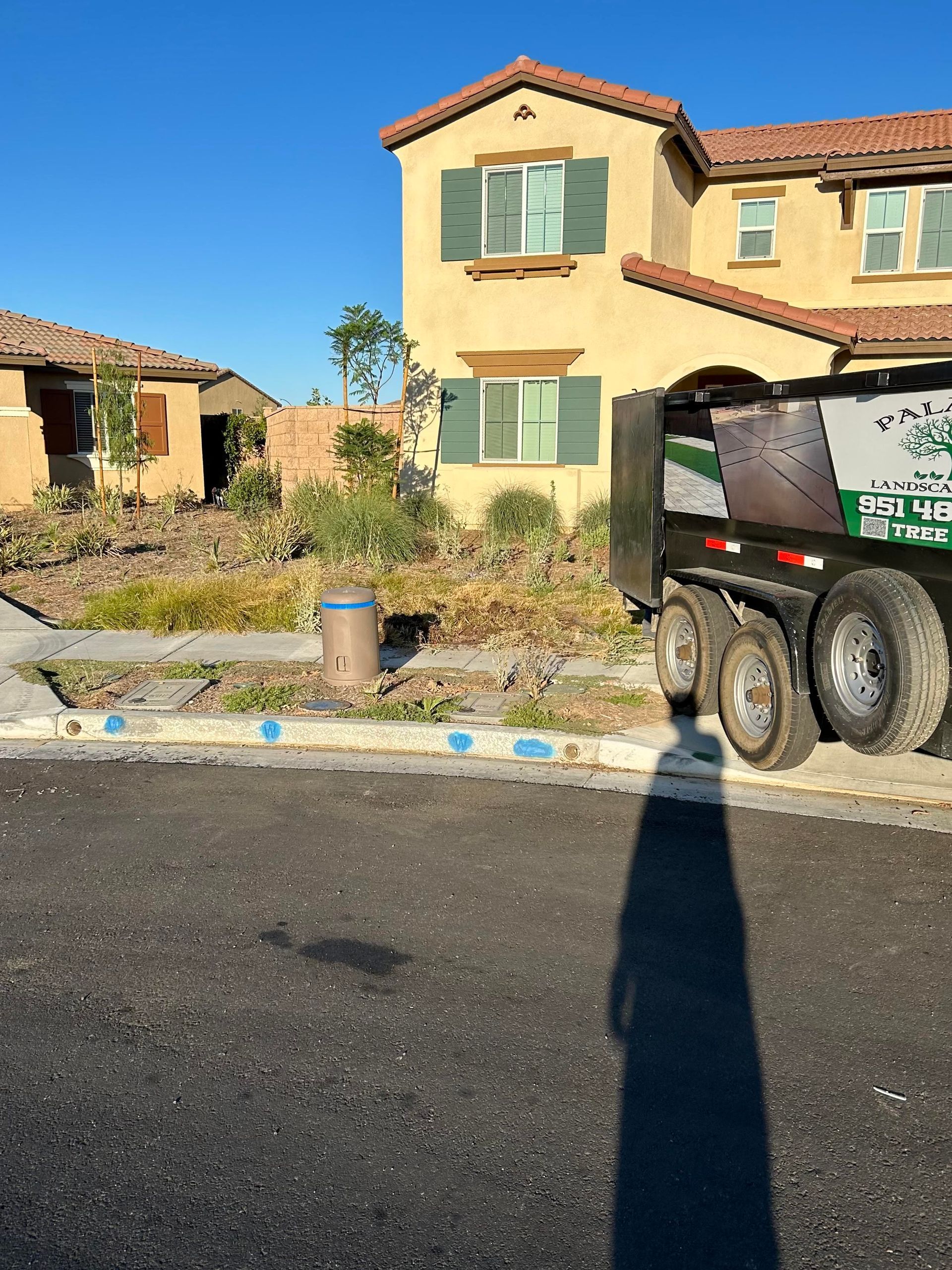 A dumpster is parked in front of a large house.
