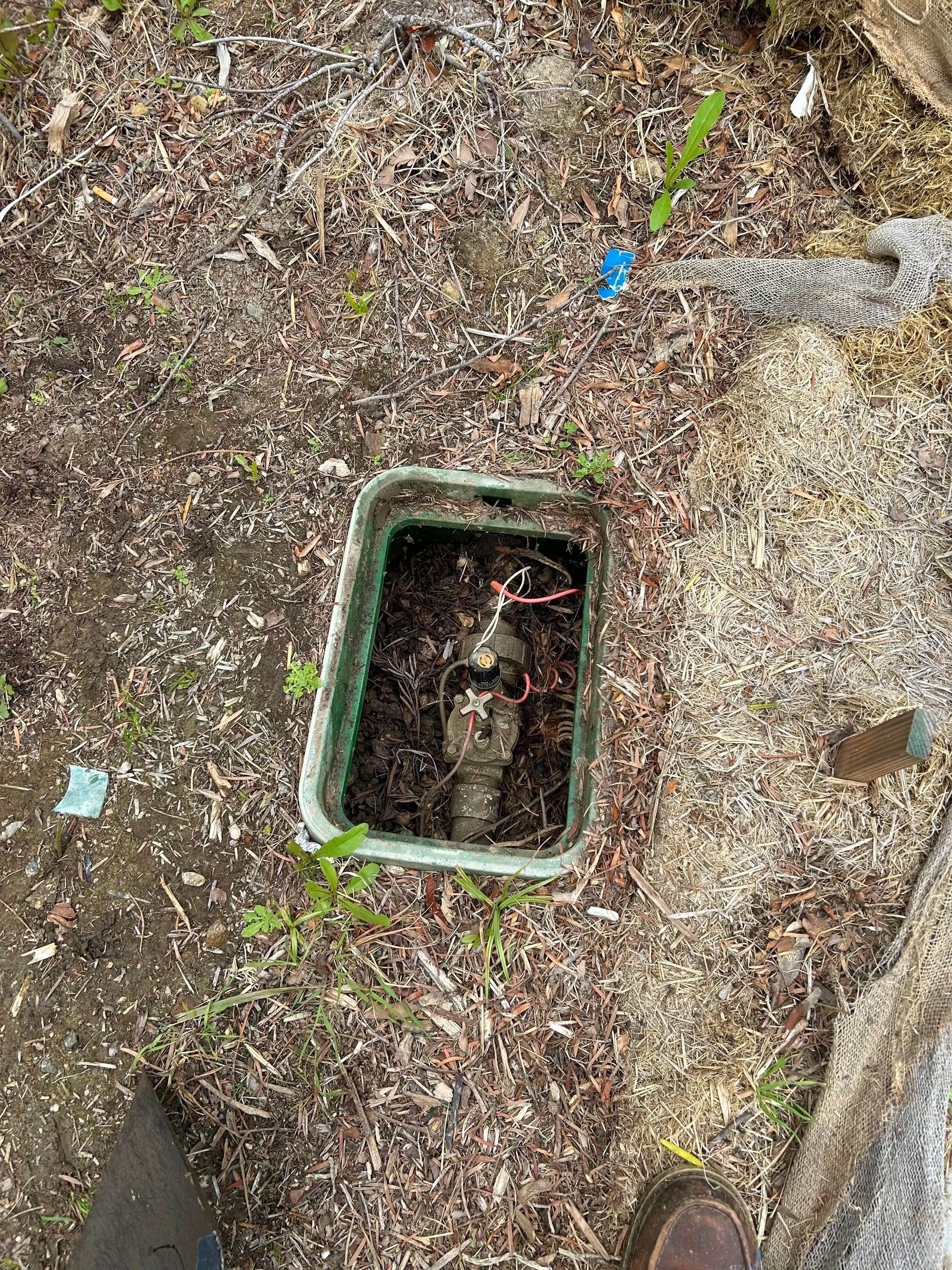 A green box is sitting on top of a pile of dirt on the ground.