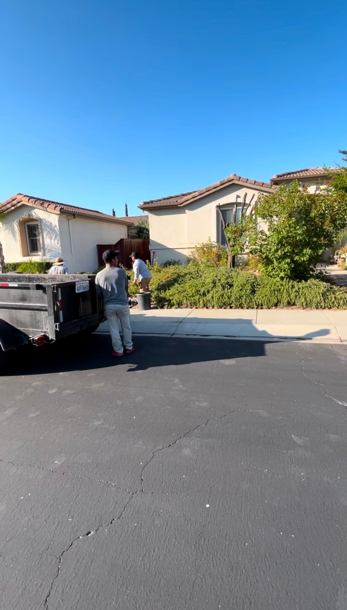 A man is standing next to a dumpster in front of a house.