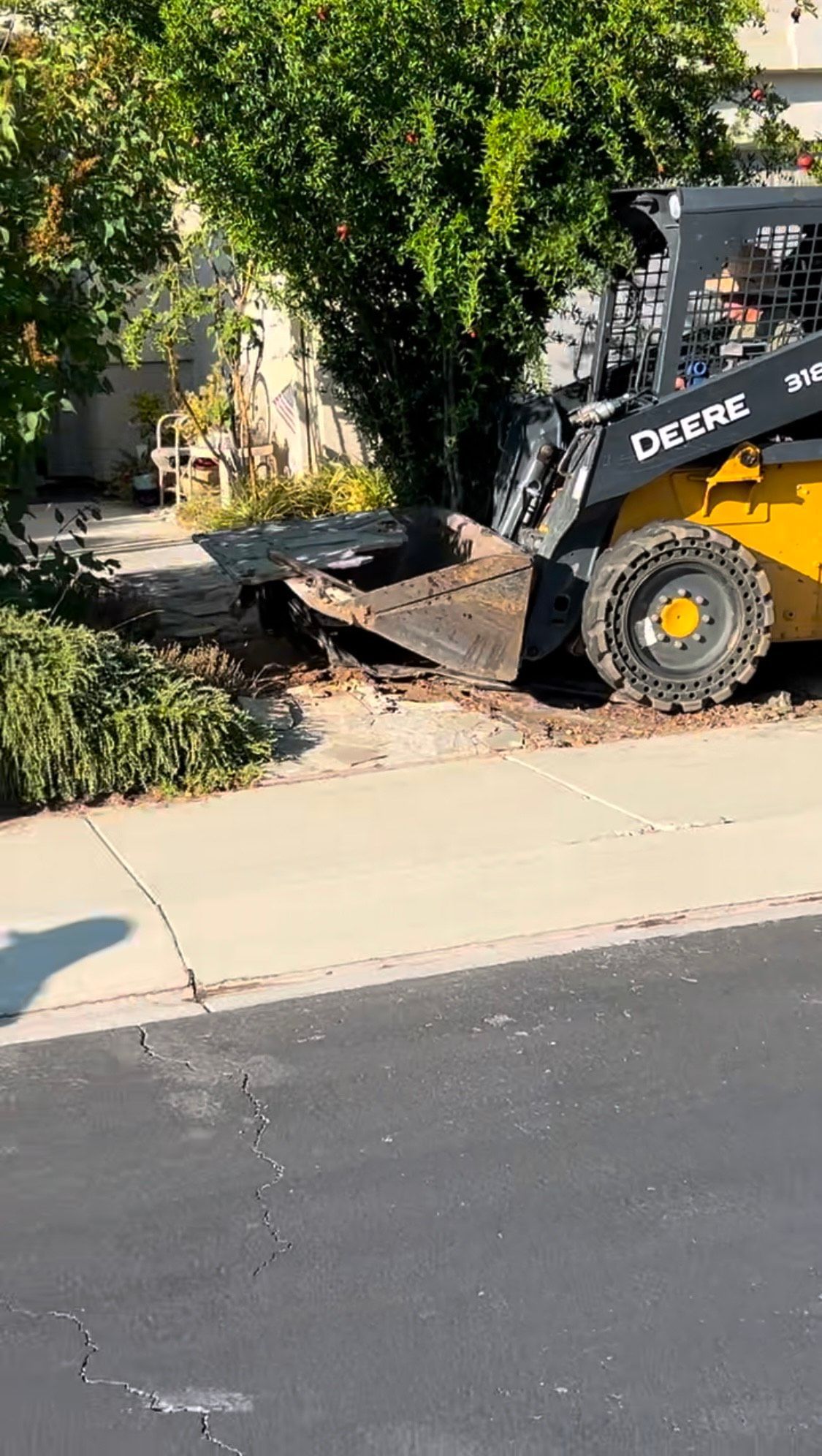A yellow skid steer is parked in a driveway.