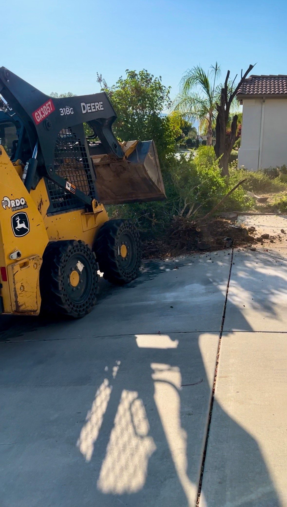 A yellow skid steer is parked in a driveway.