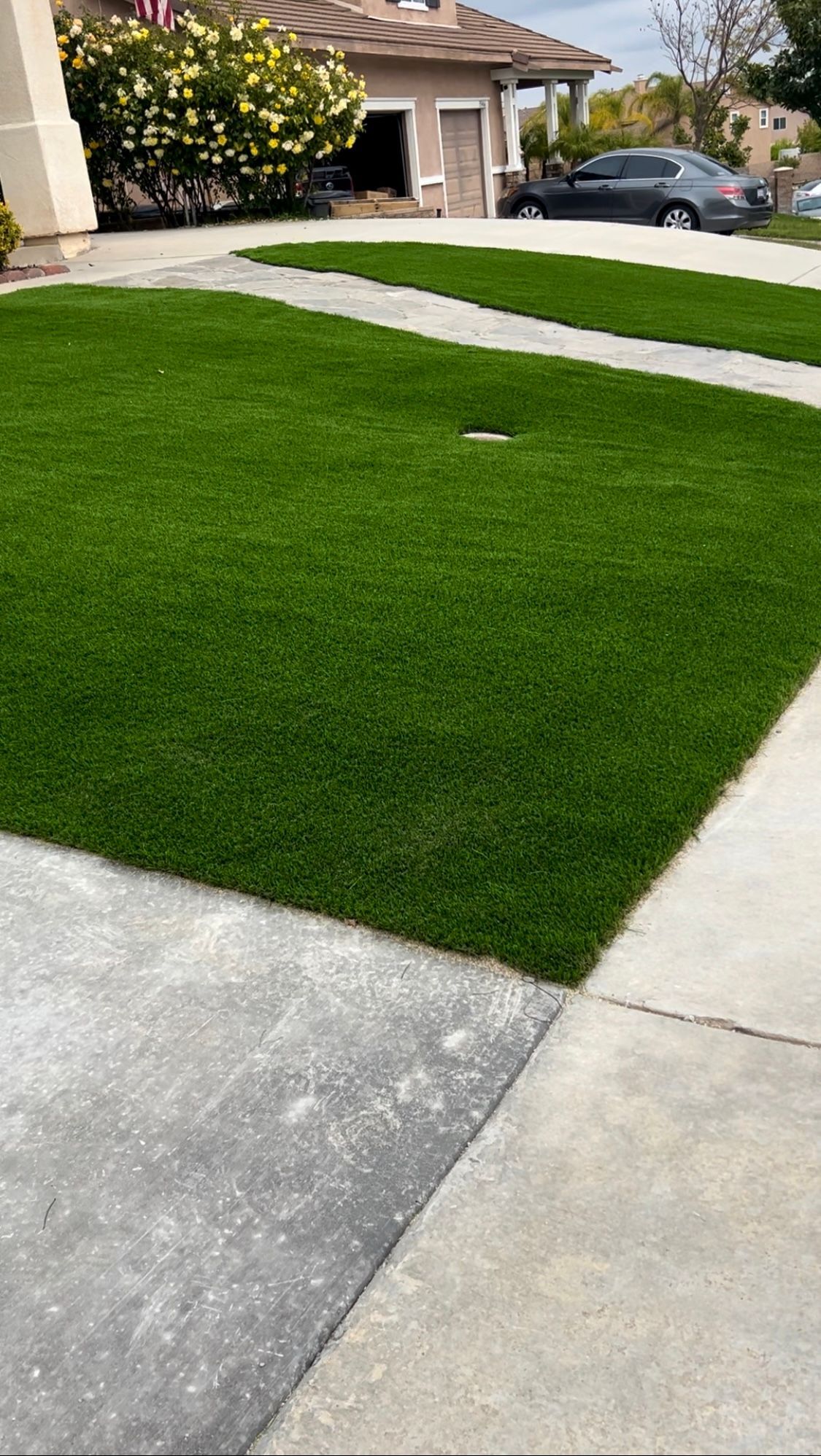 Suburban house with a bright green lawn and concrete driveway under overcast light