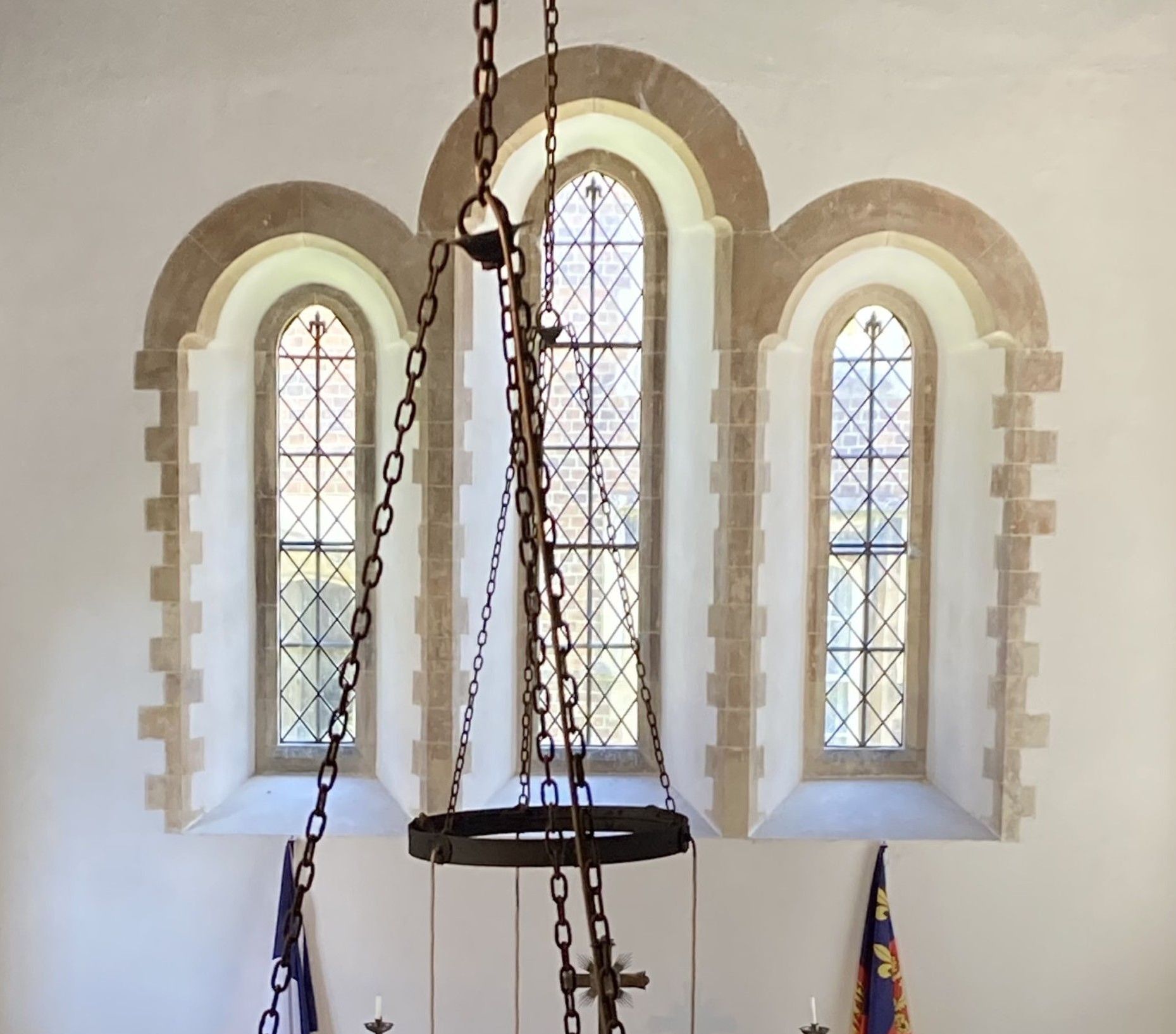 A stained glass window in a church with chains hanging from the ceiling