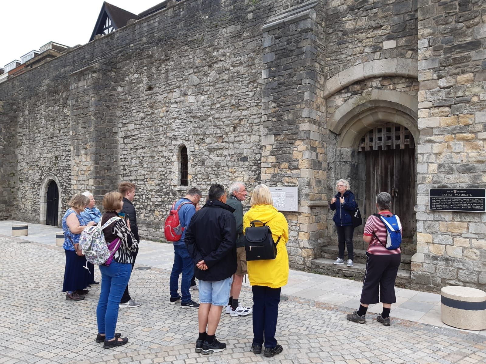A group of people are standing in front of a stone building.