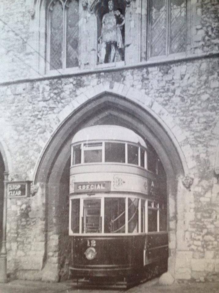 A black and white photo of a double decker bus parked in front of a stone building.