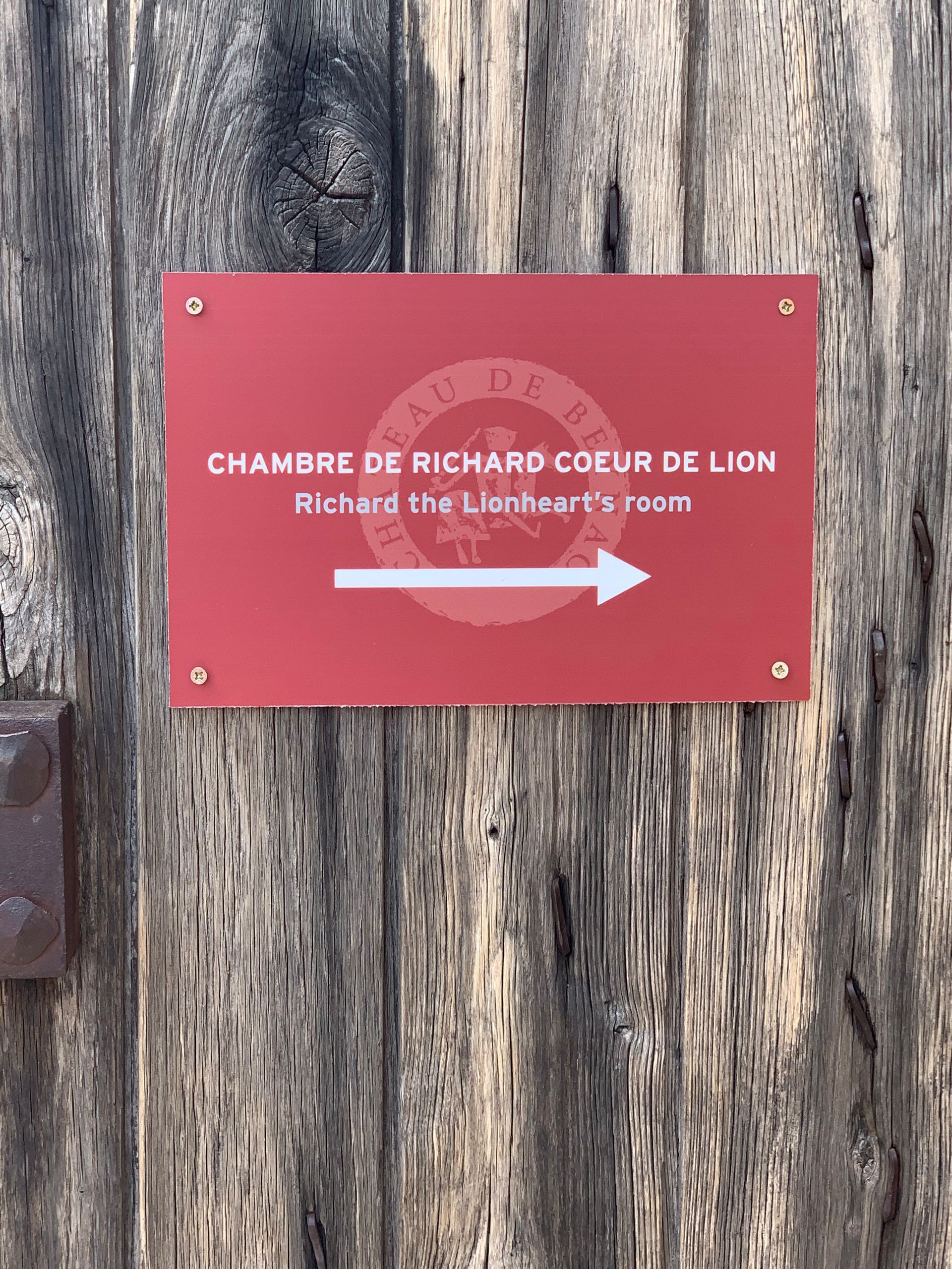 A red sign with an arrow pointing to the right on a wooden wall.