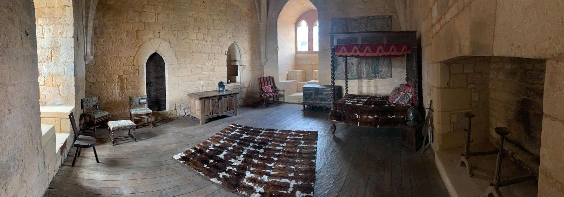 A large room with a bed , chairs , a rug and a fireplace.