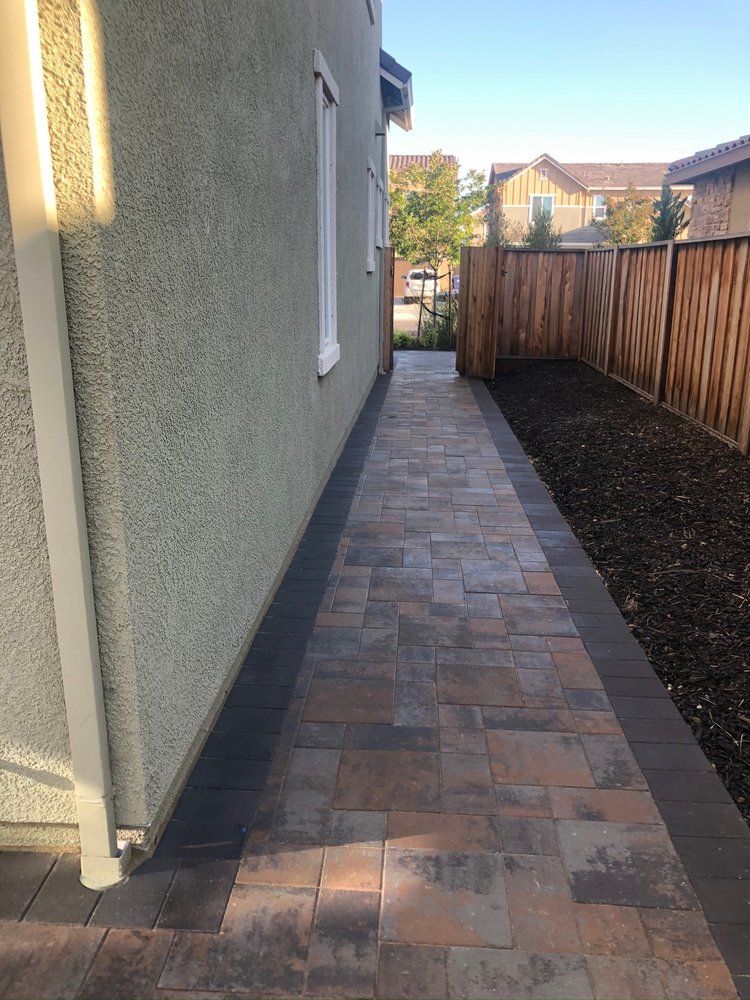 A sidewalk leading to a house with a wooden fence.