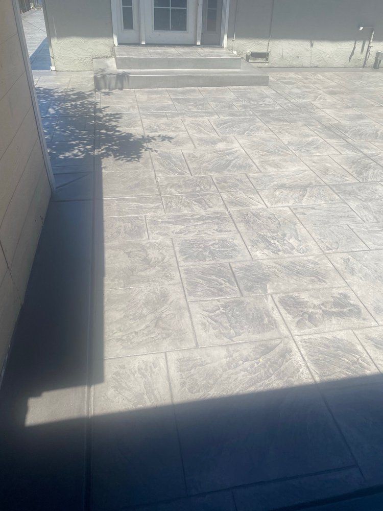 A concrete patio in front of a house with stairs and a door.