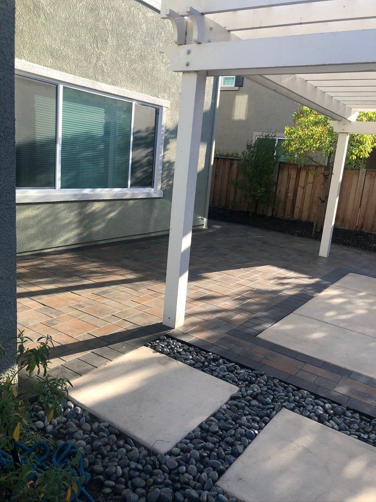 A patio with a pergola and a window in the backyard of a house.
