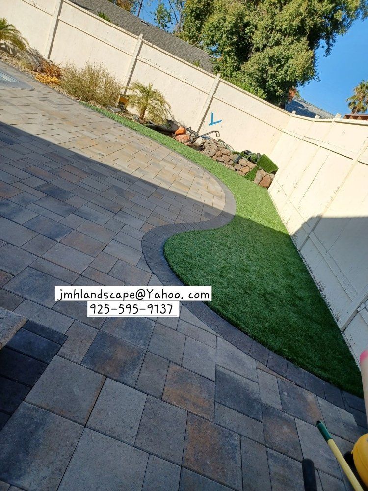 A patio with a lawn and a fence in the background.