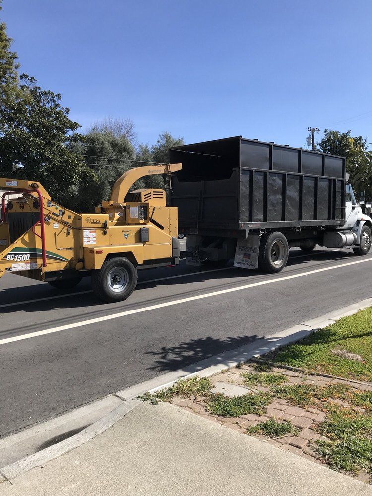 A truck with a chipper attached to it is parked on the side of the road.