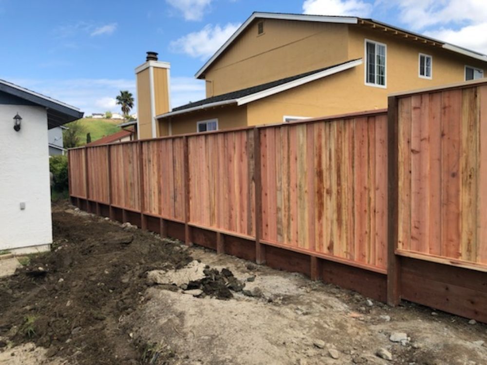 A wooden fence is in front of a house.