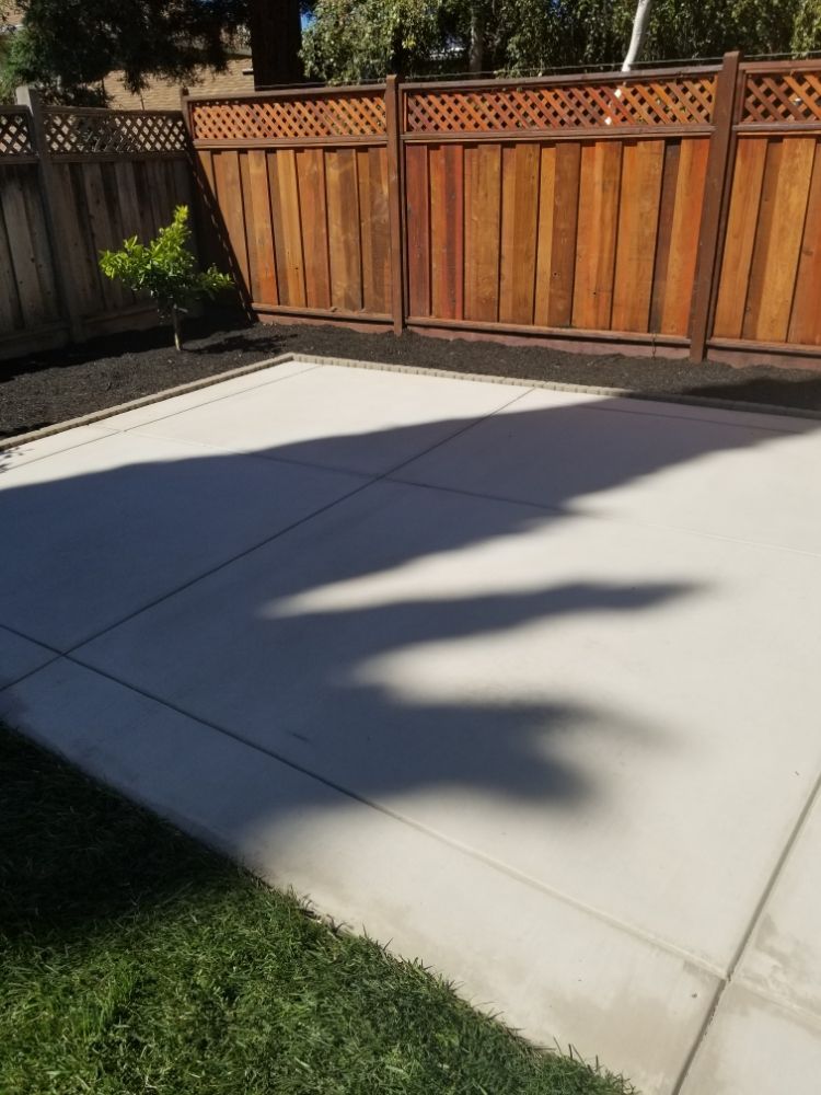 A concrete patio with a wooden fence in the background