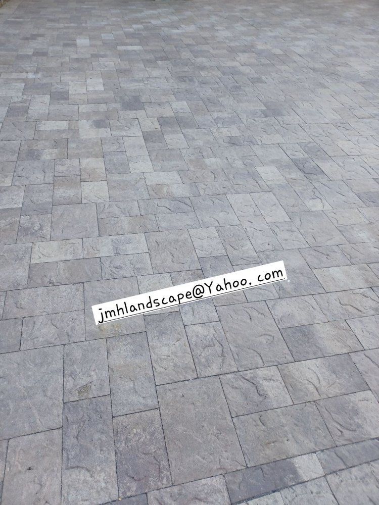 A picture of a brick driveway with a phone number on it.