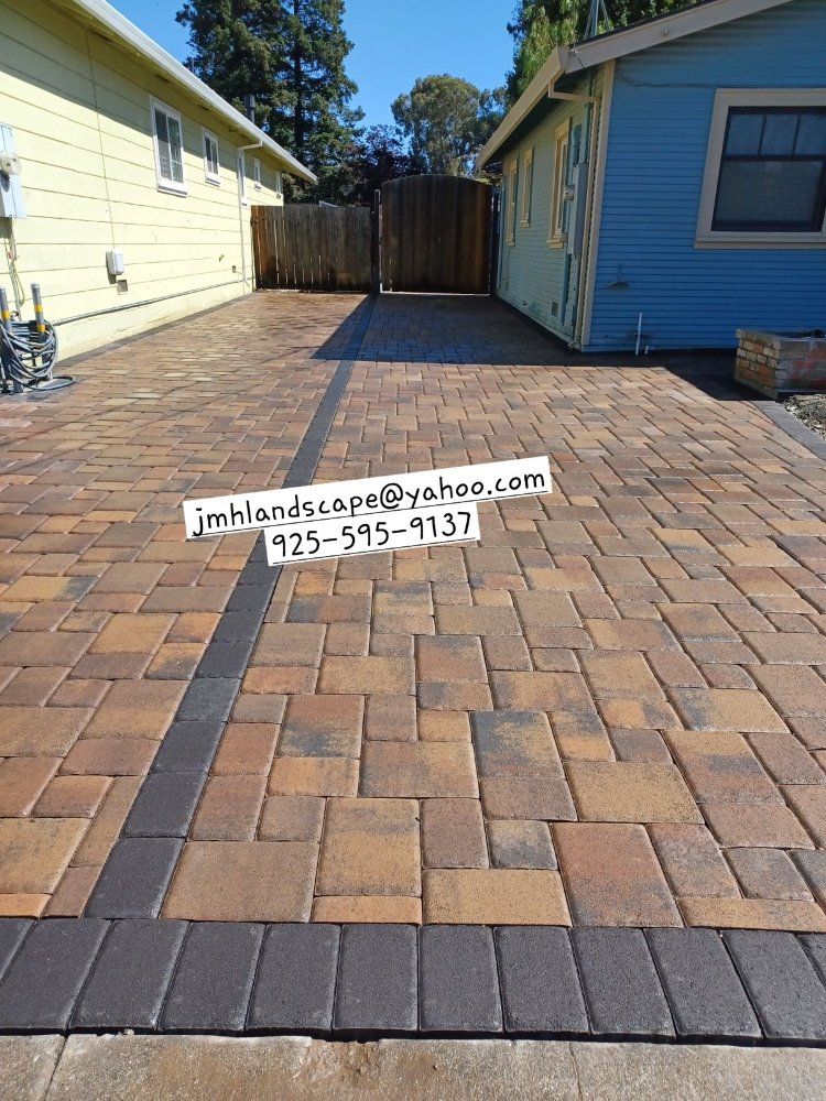 A brick driveway in front of a blue house