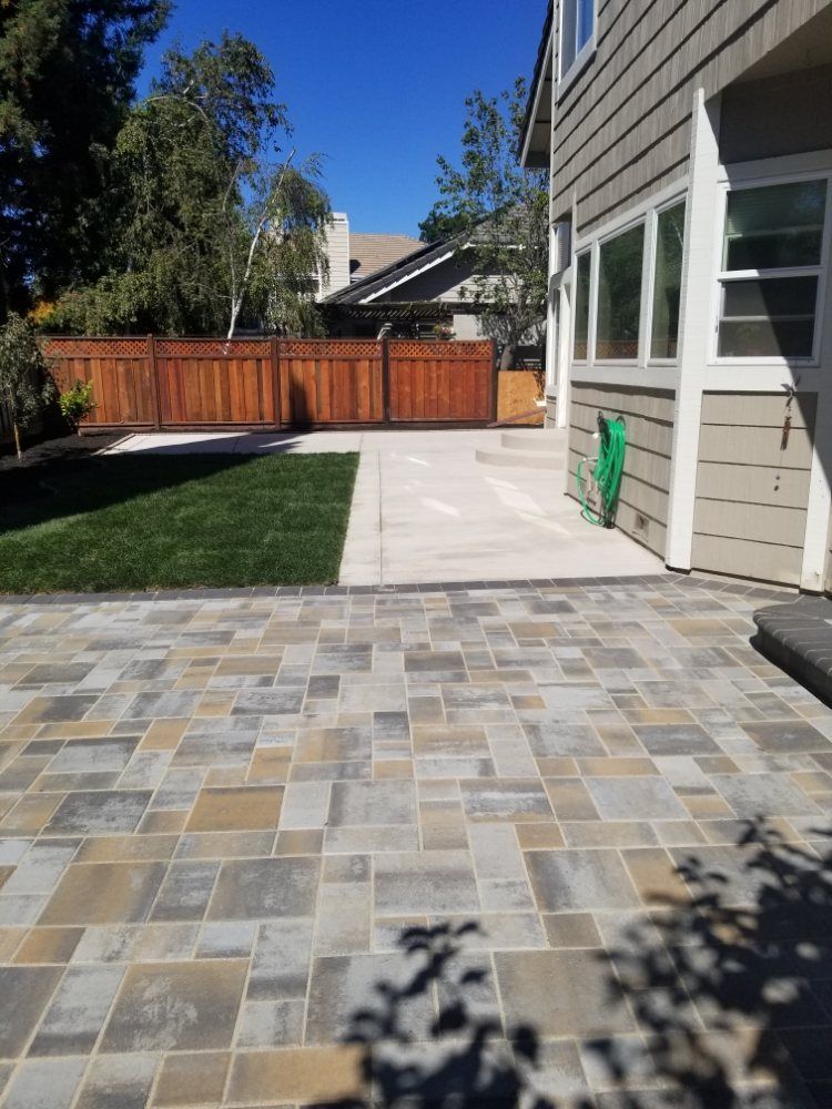 A house with a fence and a patio in front of it.