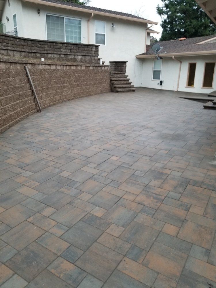 A patio with a brick wall and stairs in front of a house.