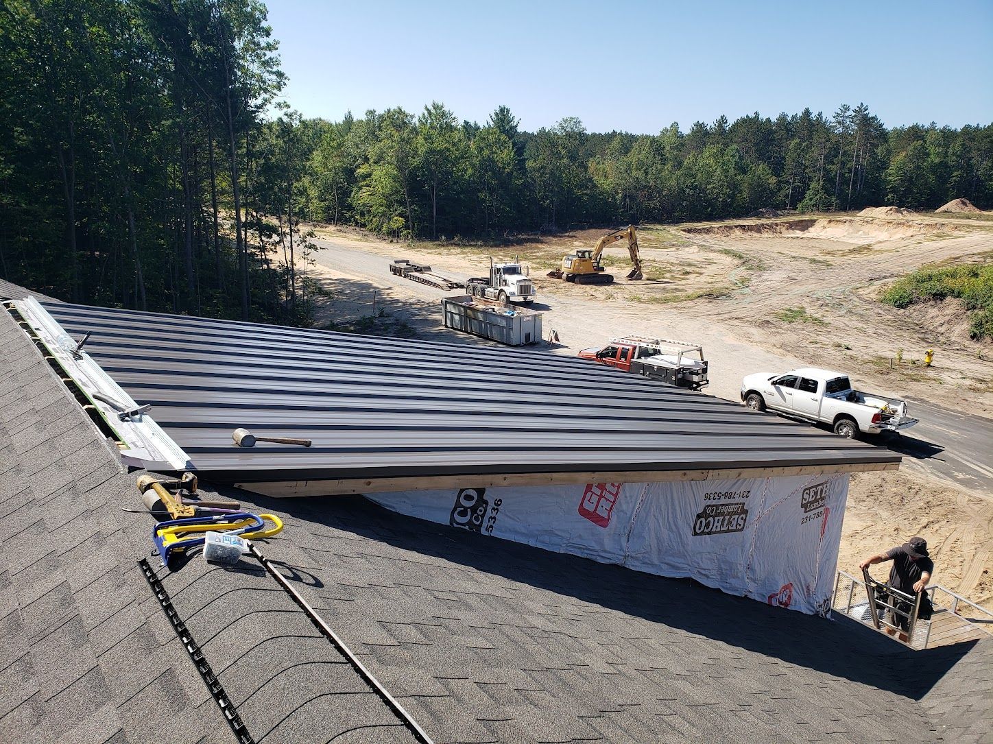 Roofing crew repairing a roof with exposed underlayment on a house in a cleared lot
