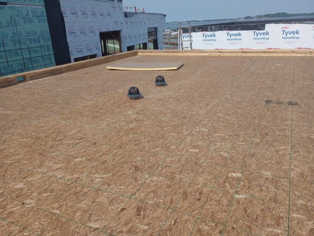 Flat rooftop with brown roofing, two vents, and a skylight near the back edge.