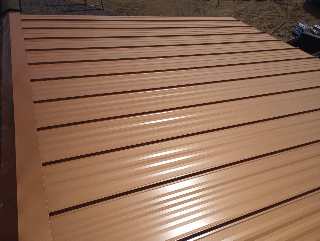 Brown corrugated metal roof panels laid out on the ground outdoors
