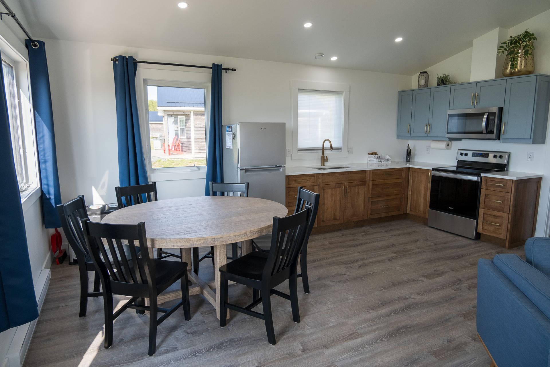 Cottage kitchen area, with fridge, sink under the window, stove, oven, microwave, cupboards, and a kitchen table.