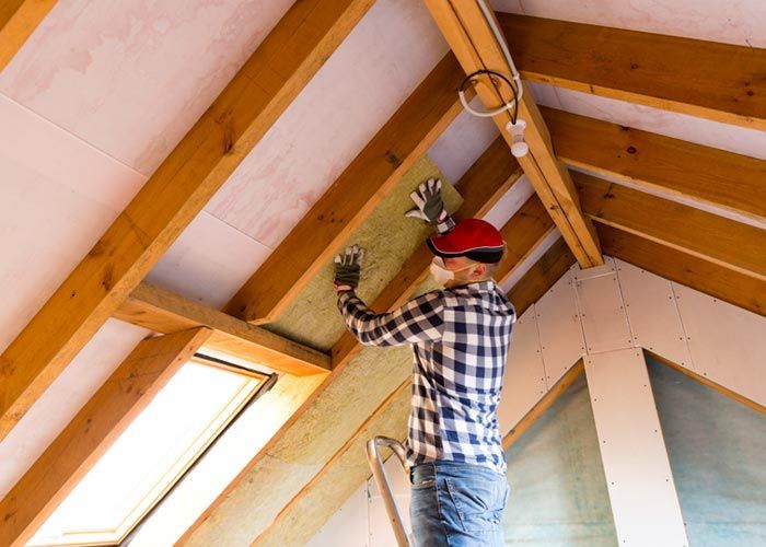 worker installing insulation in attic