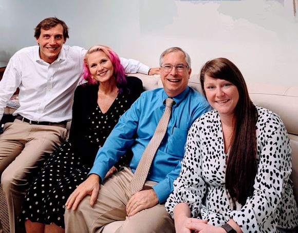 Couple embraces at a table, meeting with a financial advisor in an office setting.