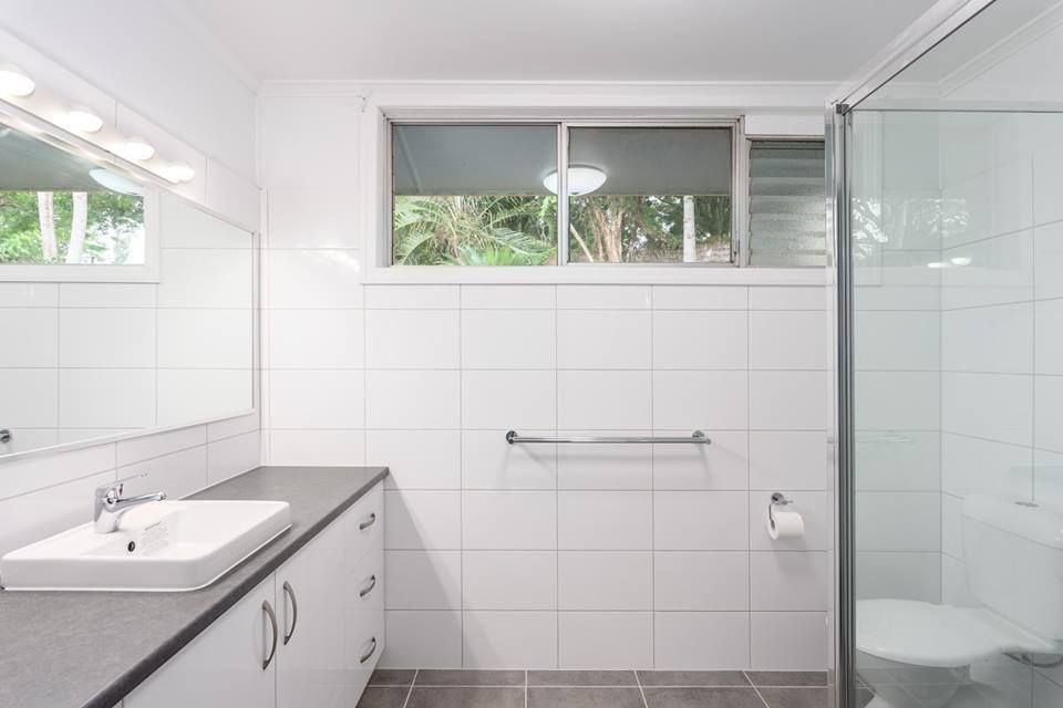 A White-tiled Bathroom With a Vanity, Sink, Mirror, Towel Bar, Toilet — Craftsmen Kitchens in Monkland, Qld
