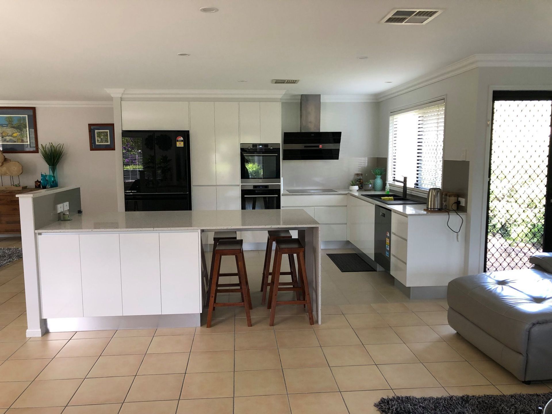 Kitchen With an Island, Two Wooden Bar Stools, Stainless Steel Appliances — Craftsmen Kitchens In Monkland, QLD