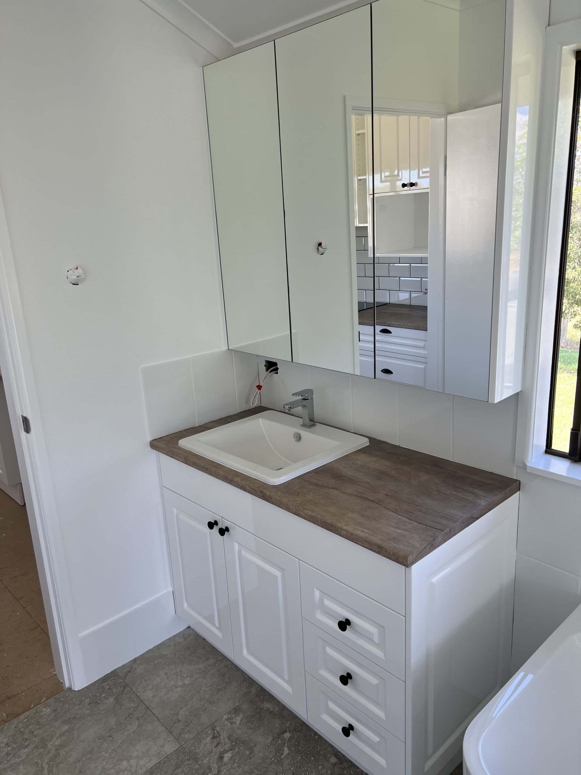 A Bathroom Vanity With a White Cabinet, Wood-look Countertop — Craftsmen Kitchens In Monkland, QLD