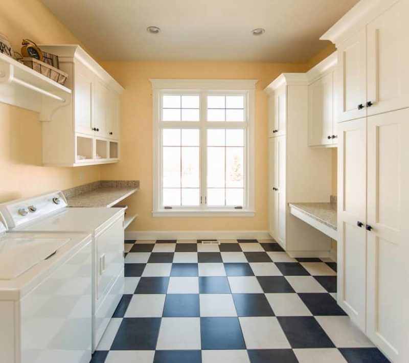 Laundry Room With White Cabinets, Yellow Walls, and a Checkered Floor