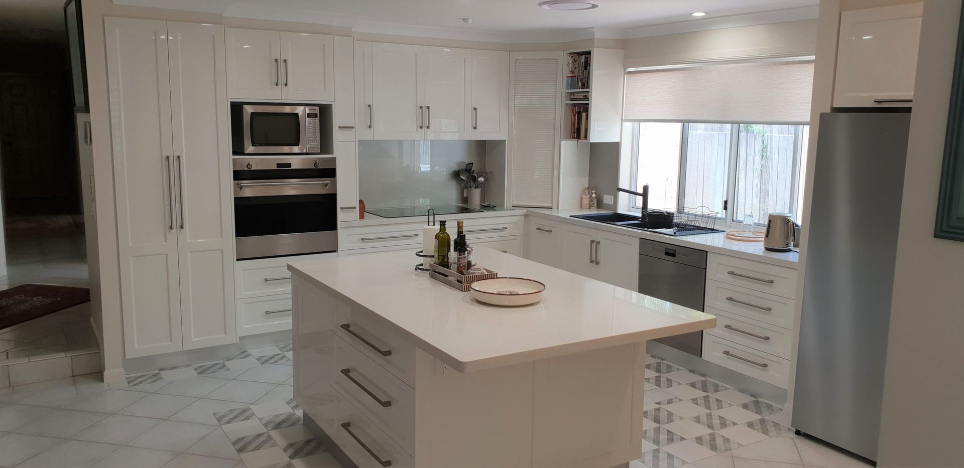 A Modern Kitchen With White Cabinets, a Central Island — Craftsmen Kitchens In Monkland, QLD
