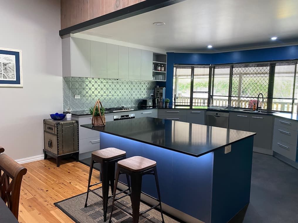A Modern Kitchen With a Blue Island, Black Countertop, Grey Cabinetry — Craftsmen Kitchens In Monkland, QLD