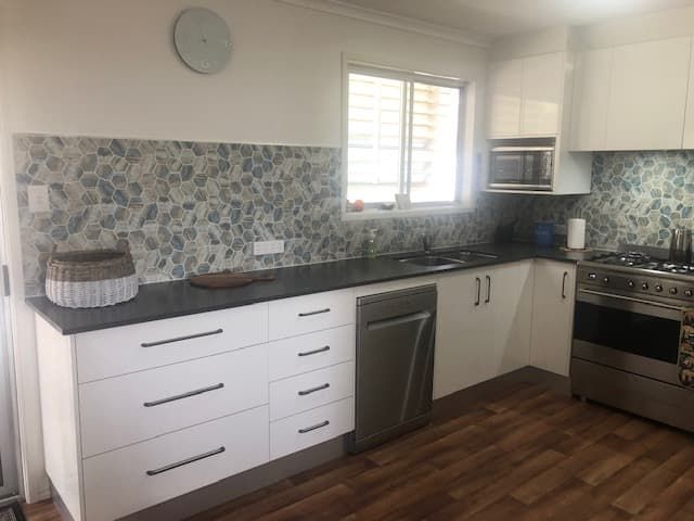 A Modern Kitchen With White Cabinets, Dark Countertops — Craftsmen Kitchens In Monkland, QLD