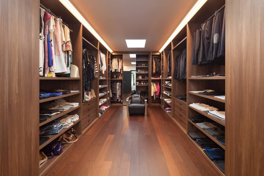 A Spacious, Well-lit Walk-in Closet With Dark Wood Shelving, Hanging Clothes — Craftsmen Kitchens In Monkland, QLD