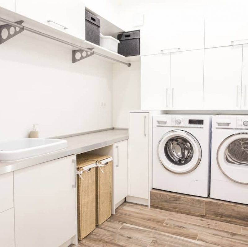 A Bright, Modern Laundry Room With White Cabinets, Stacked Washer and Dryer — Craftsmen Kitchens In Monkland, QLD