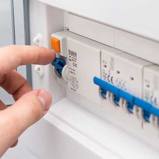 A close up of a person 's hand pressing a button on an electrical box.