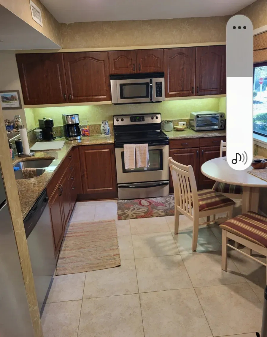 Kitchen with dark brown cabinets, stainless steel appliances, and a small dining table.
