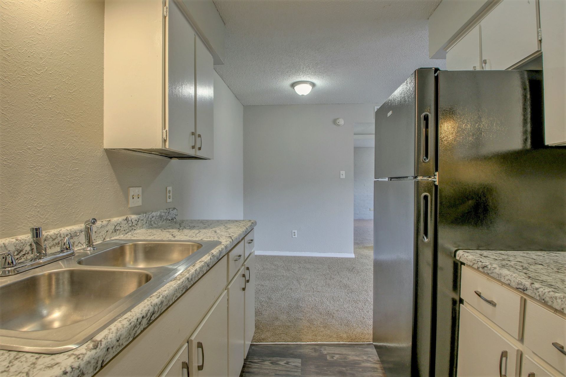 A kitchen with two sinks , a refrigerator , and granite counter tops.