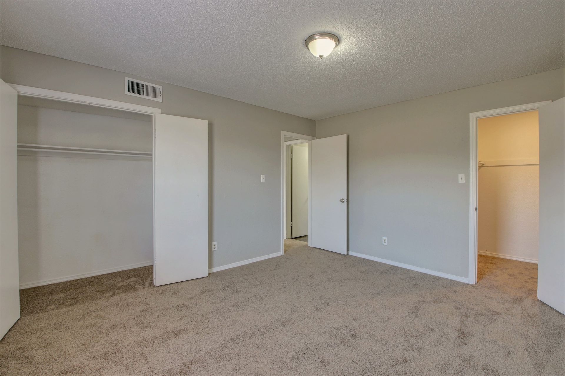 An empty bedroom with a closet and a walk in closet.