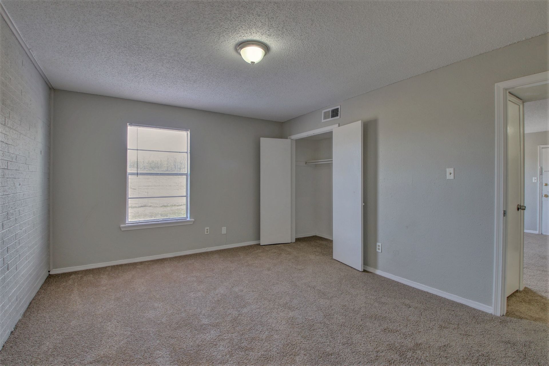 An empty bedroom with a closet and a window.