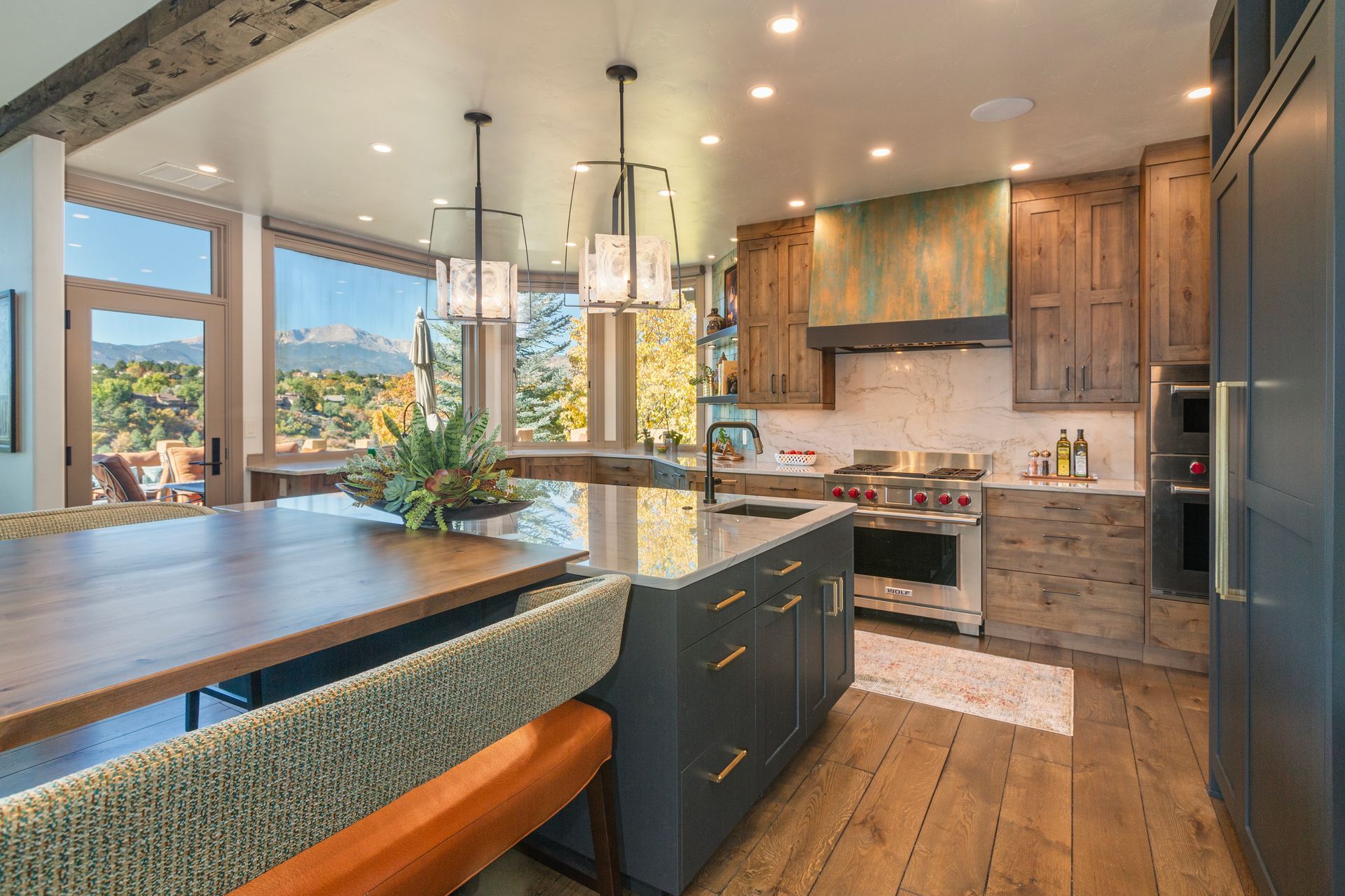Modern kitchen with island, wood cabinets, pendant lights, and large windows overlooking a scenic view