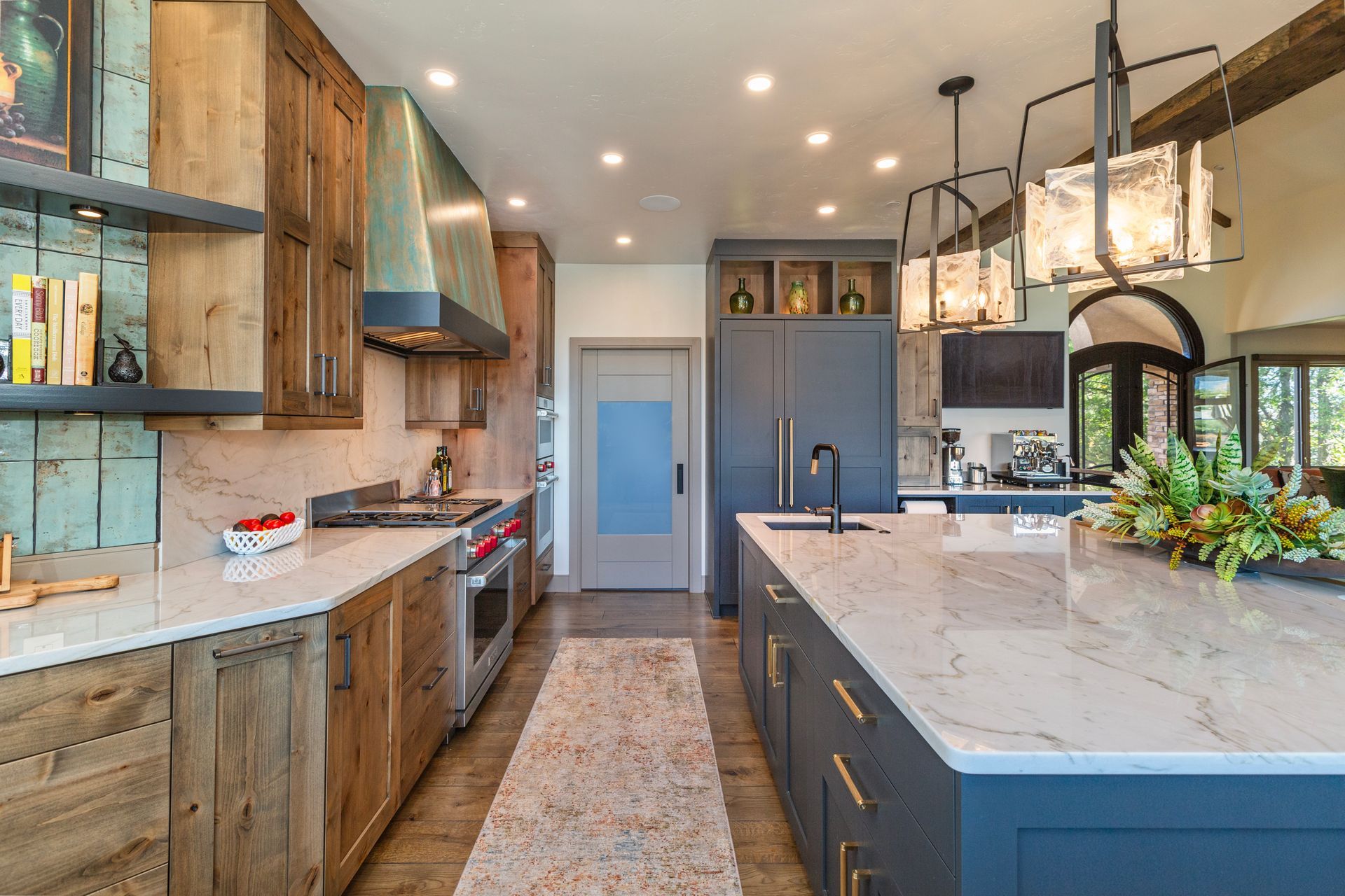 Modern kitchen with navy island, wood cabinets, marble countertops, and pendant lights