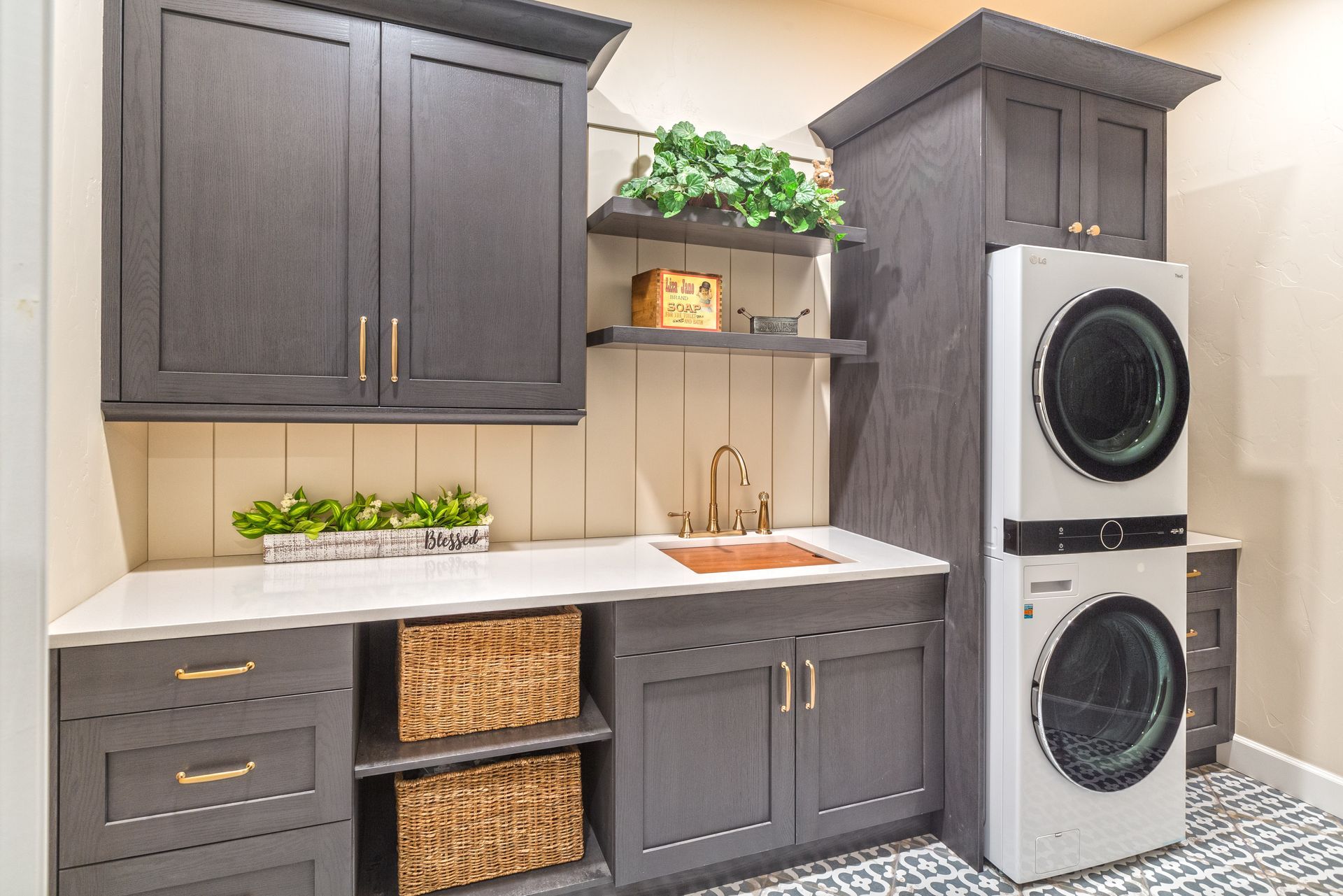 Laundry room with dark cabinets, white countertop, stacked washer and dryer, and woven storage baskets.