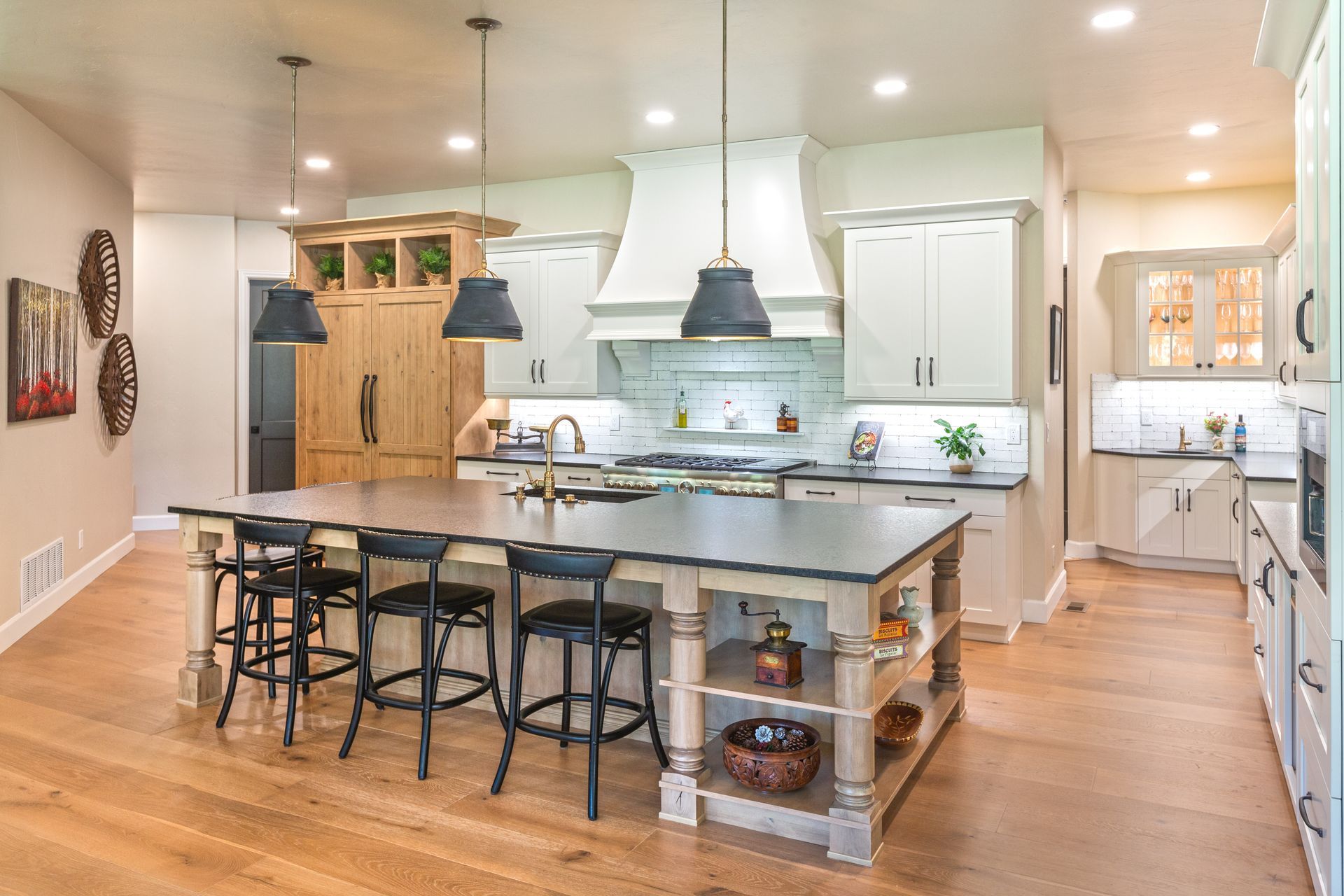 Bright modern kitchen with large island, pendant lights, wood floors, and stainless steel appliances