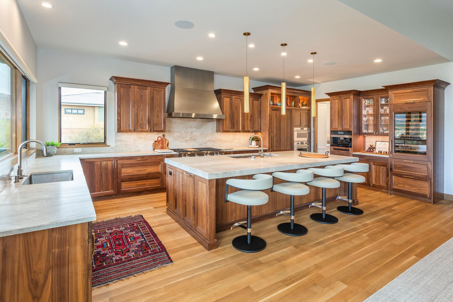 Spacious modern kitchen with wood cabinetry, large island, bar stools, and stainless steel appliances
