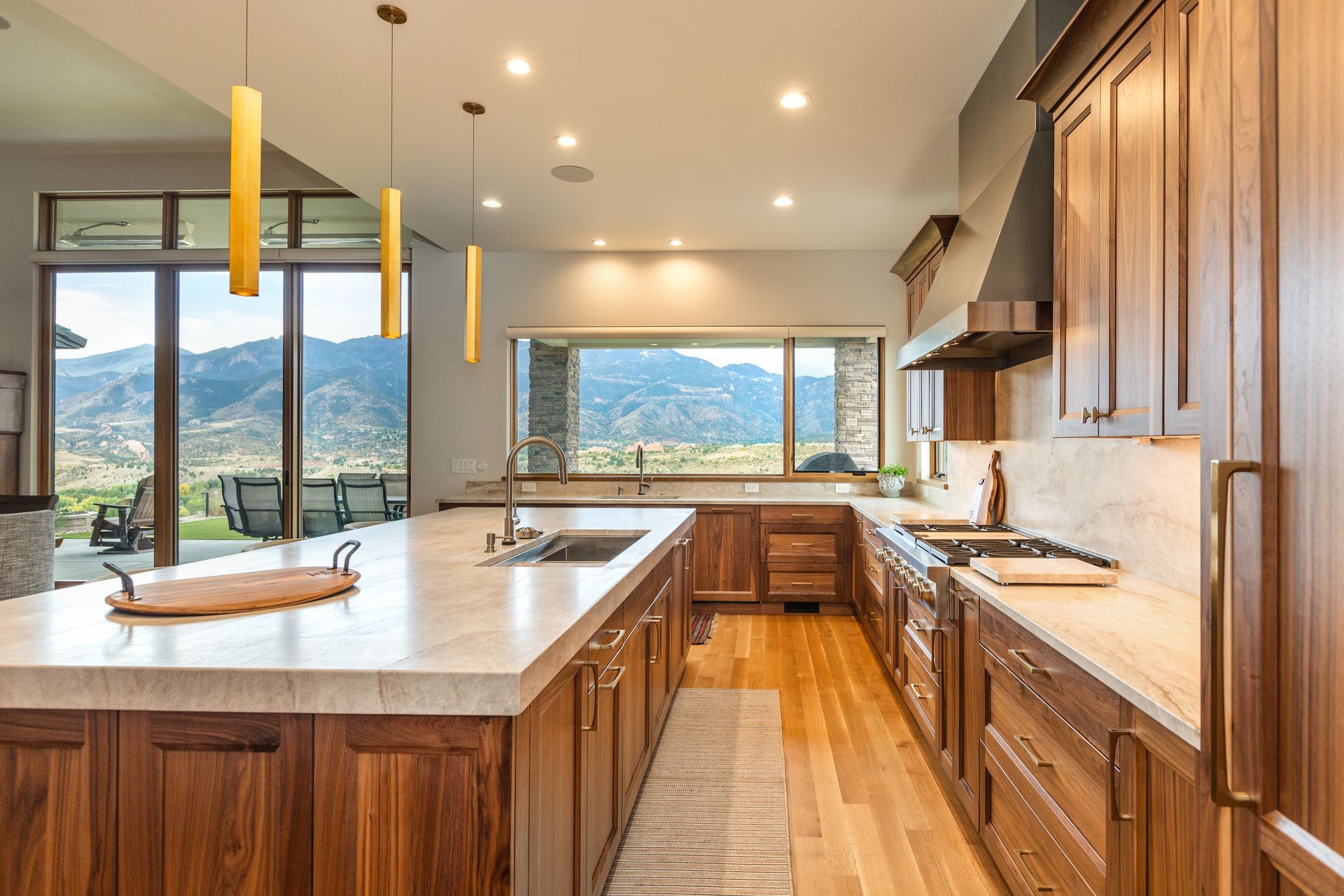 Modern kitchen with wood cabinets, marble island, and mountain view through large windows