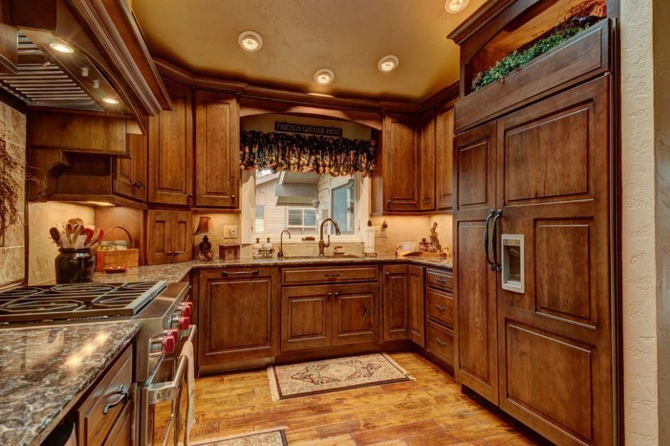 Warm wood kitchen with granite counters, stainless appliances, and a window over the sink