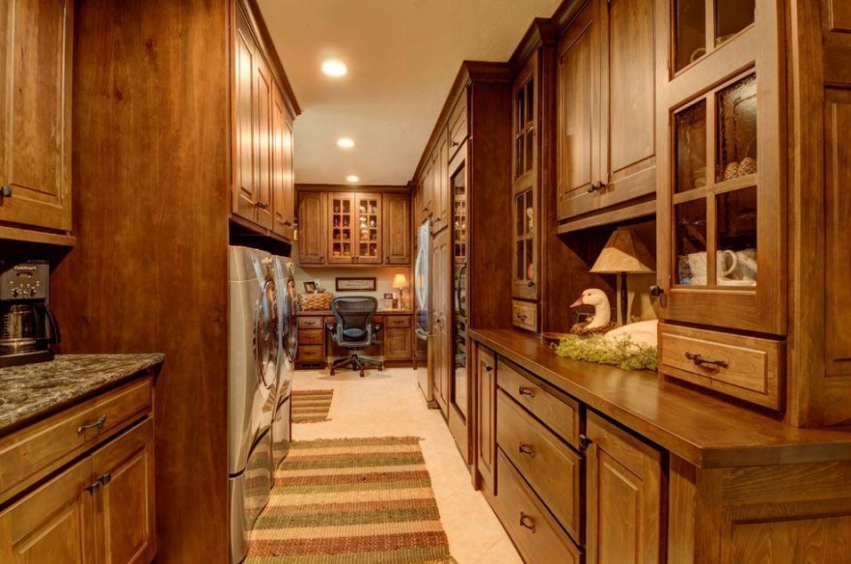 Warm wood kitchen with long galley layout, granite counters, built-in cabinets, and striped runner rug.